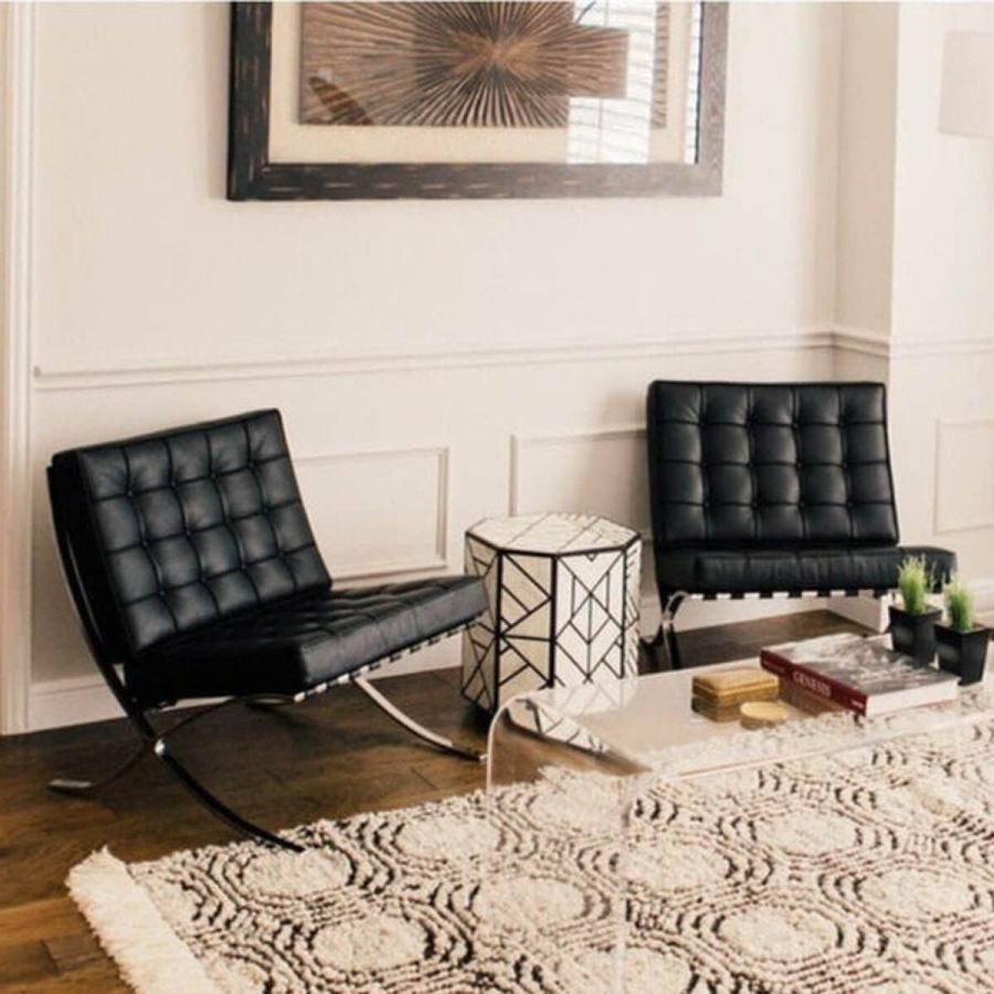 Two Barcelona chair replicas in black leather, styled in a living room beside a patterned side table