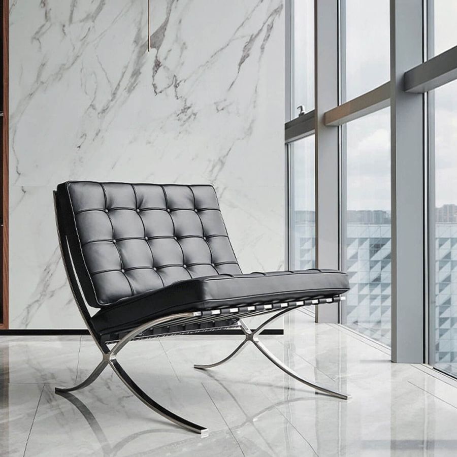 Barcelona chair replica in black leather, styled against a marble accent wall with floor-to-ceiling windows