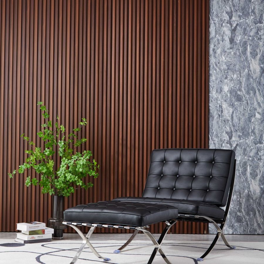 Barcelona chair replica in black leather, styled in a modern living room, alternate angle, with books and a potted plant beside the ottoman