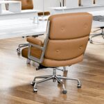 Light Brown Eames Executive Office Chair viewed from behind at an angle beside white office desks.