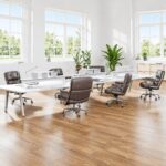 Brown Eames Executive Office Chairs arranged around white desks in a bright open-plan office.