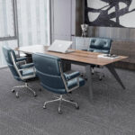 Three Dark Blue Eames Executive Office Chairs arranged around a wooden office desk.