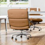 Rear view of a Light Brown Eames Executive Office Chair at a white desk in an open-plan office.